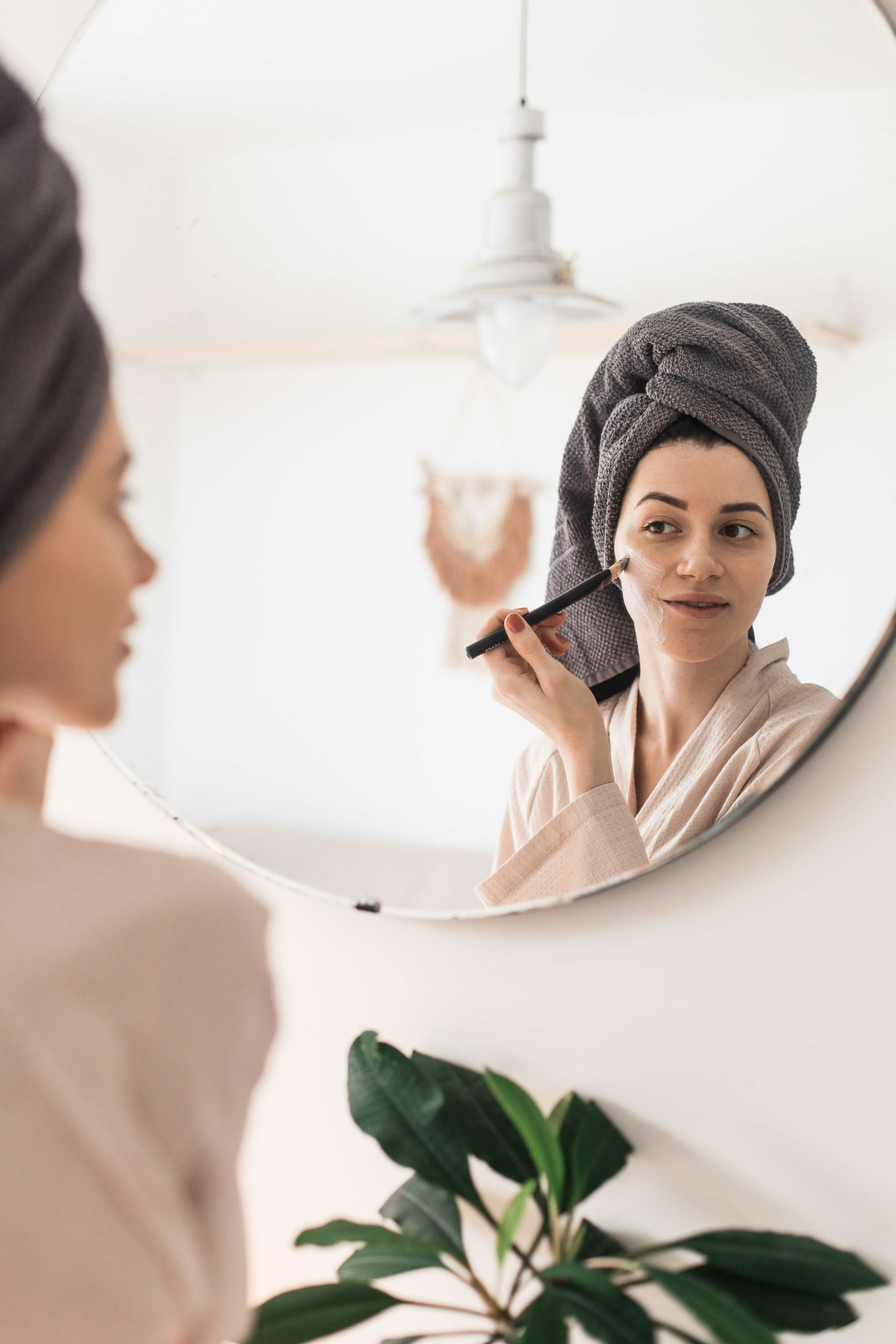 Woman in Bathrobe Applying Face Mask in Front of Mirror